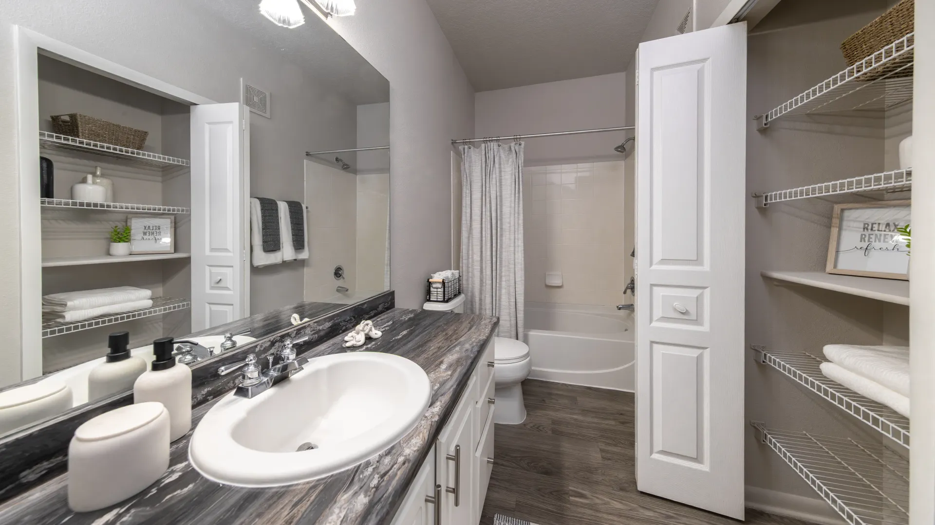 Bathroom with black-and-gray marble-style counter, white cabinetry, and dual storage closets.