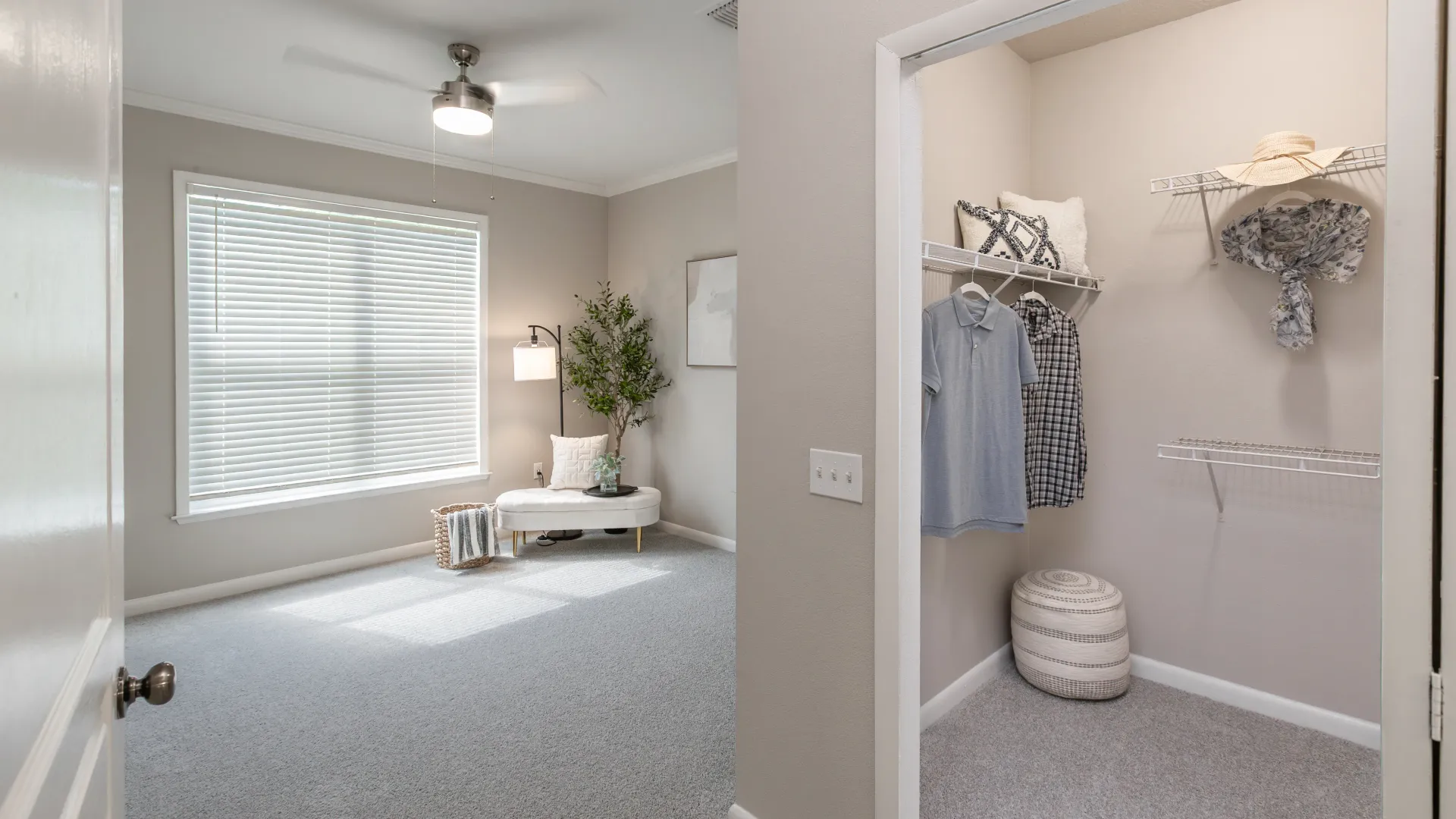 Bedroom with large window, ceiling fan, and a view into a walk-in closet at Elevate 155 Apartments.