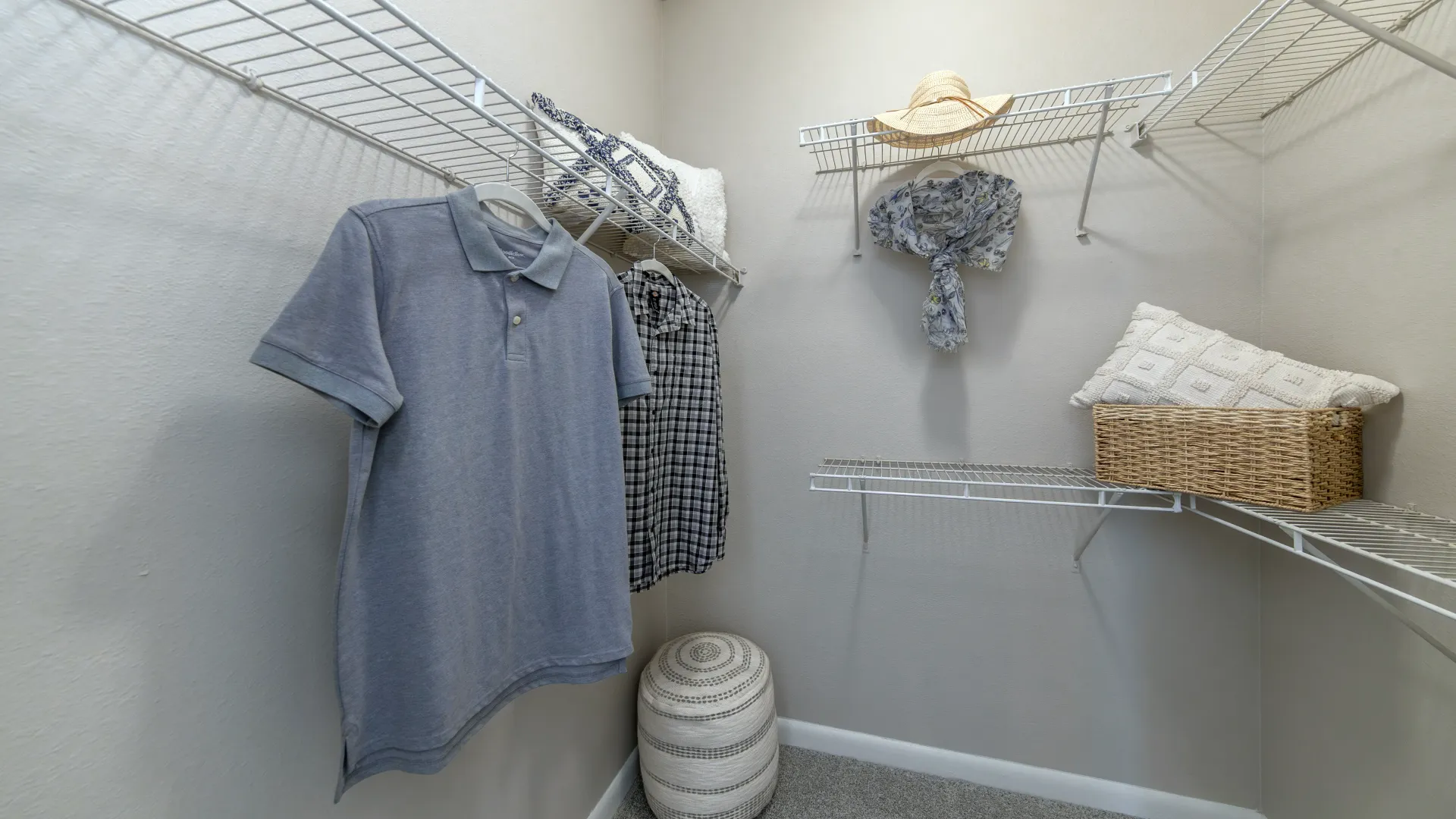 Interior of walk-in closet with hanging rods, storage baskets, and clothing neatly arranged on wire shelves.