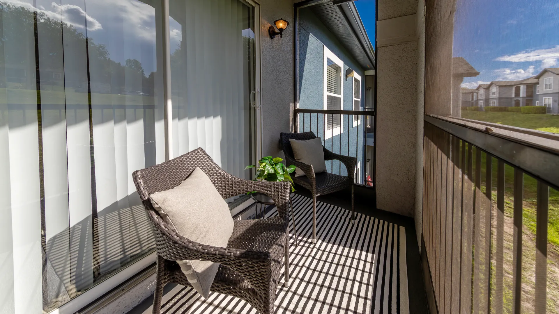 Private screened-in deck at Elevate 155 with wicker chairs, throw pillows, and striped outdoor rug.