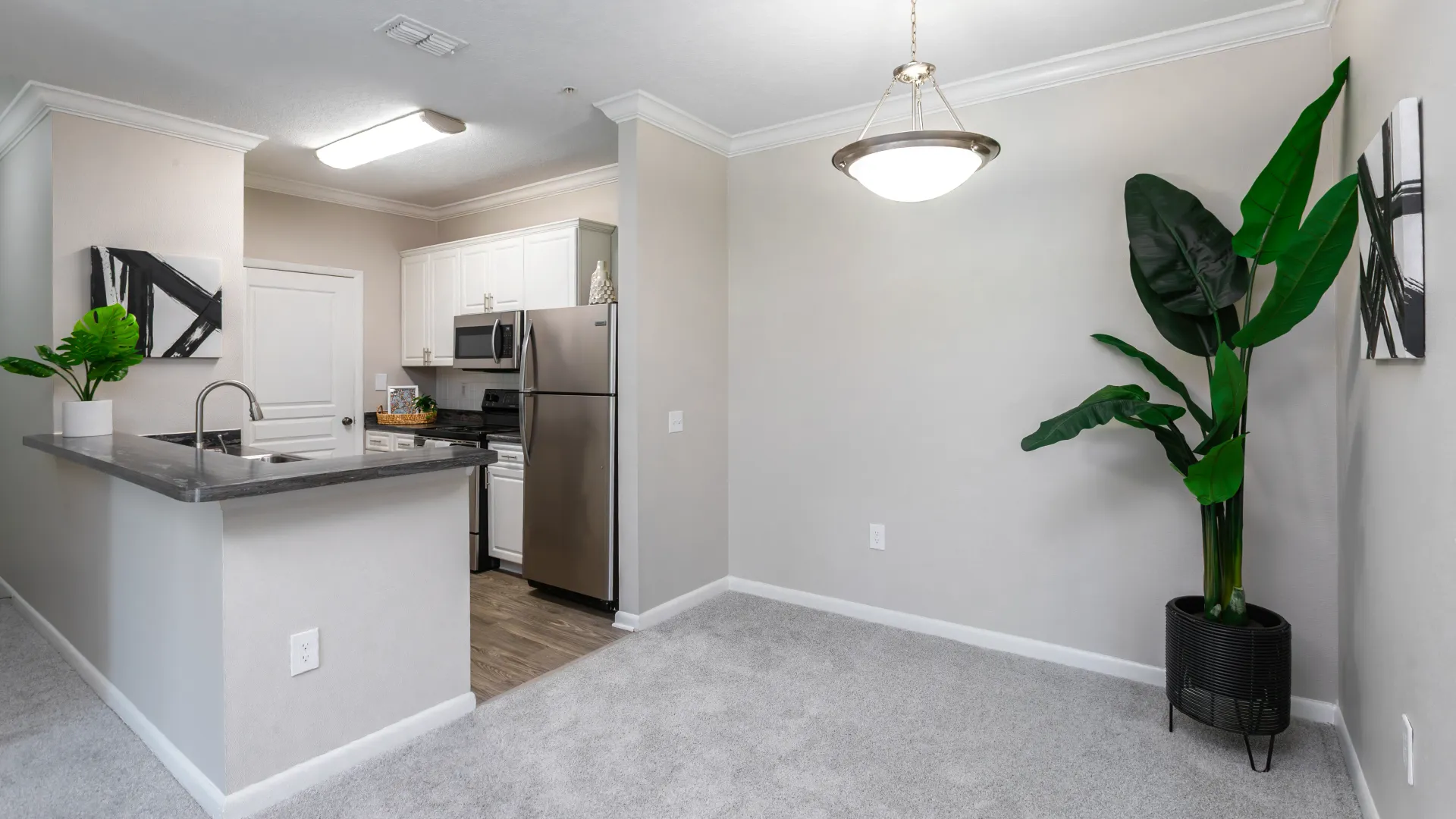 Dining area next to kitchen with stainless-steel appliances and dark countertops at Elevate 155.