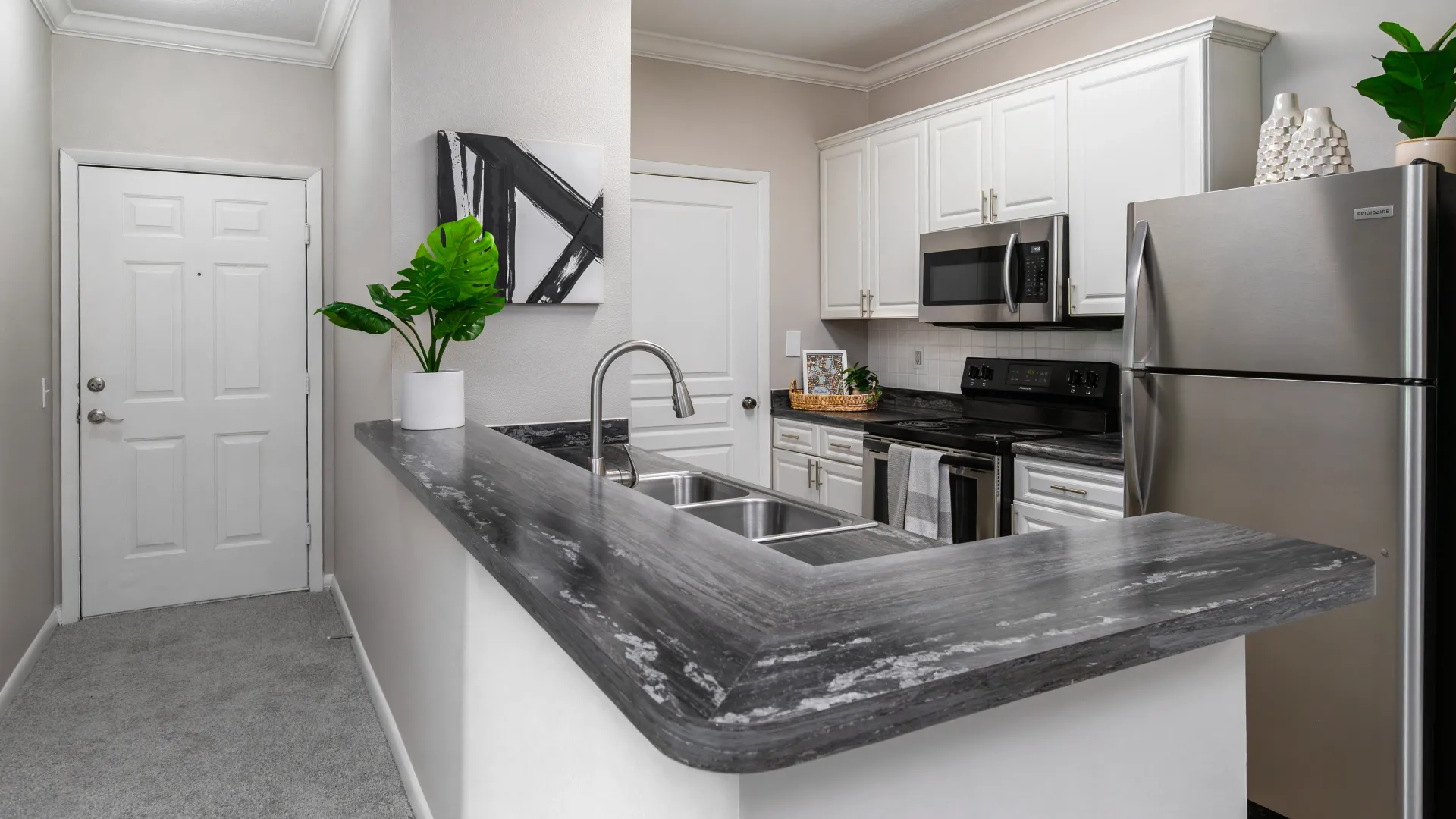 Kitchen with stainless appliances and a gray breakfast bar at Elevate 155.