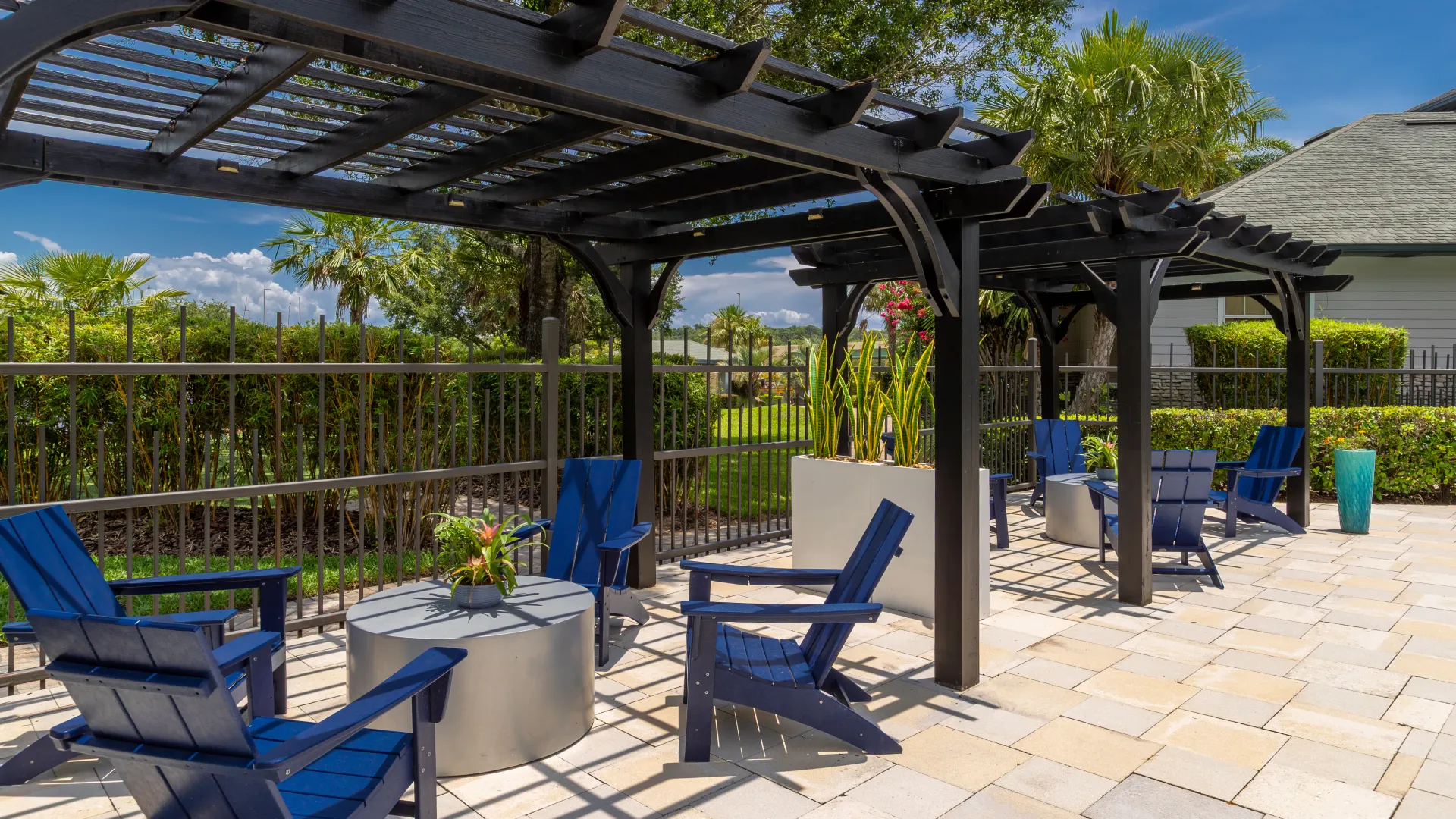 Shaded lounge area at Elevate 155 with navy Adirondack chairs and modern pergolas near the pool.