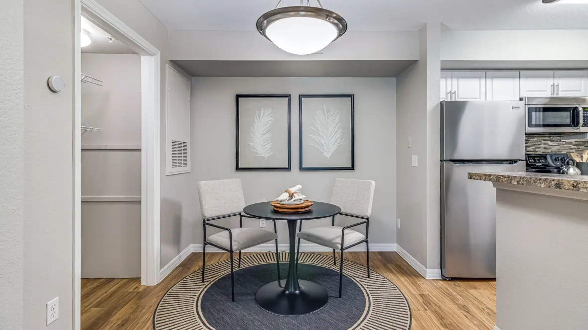 A view from the living room, admiring the dining area complete with a table and chair set with a nickel-brushed light fixture overhead for an elegant space to enjoy meals and a spacious storage closet accessible from the dining room. 
