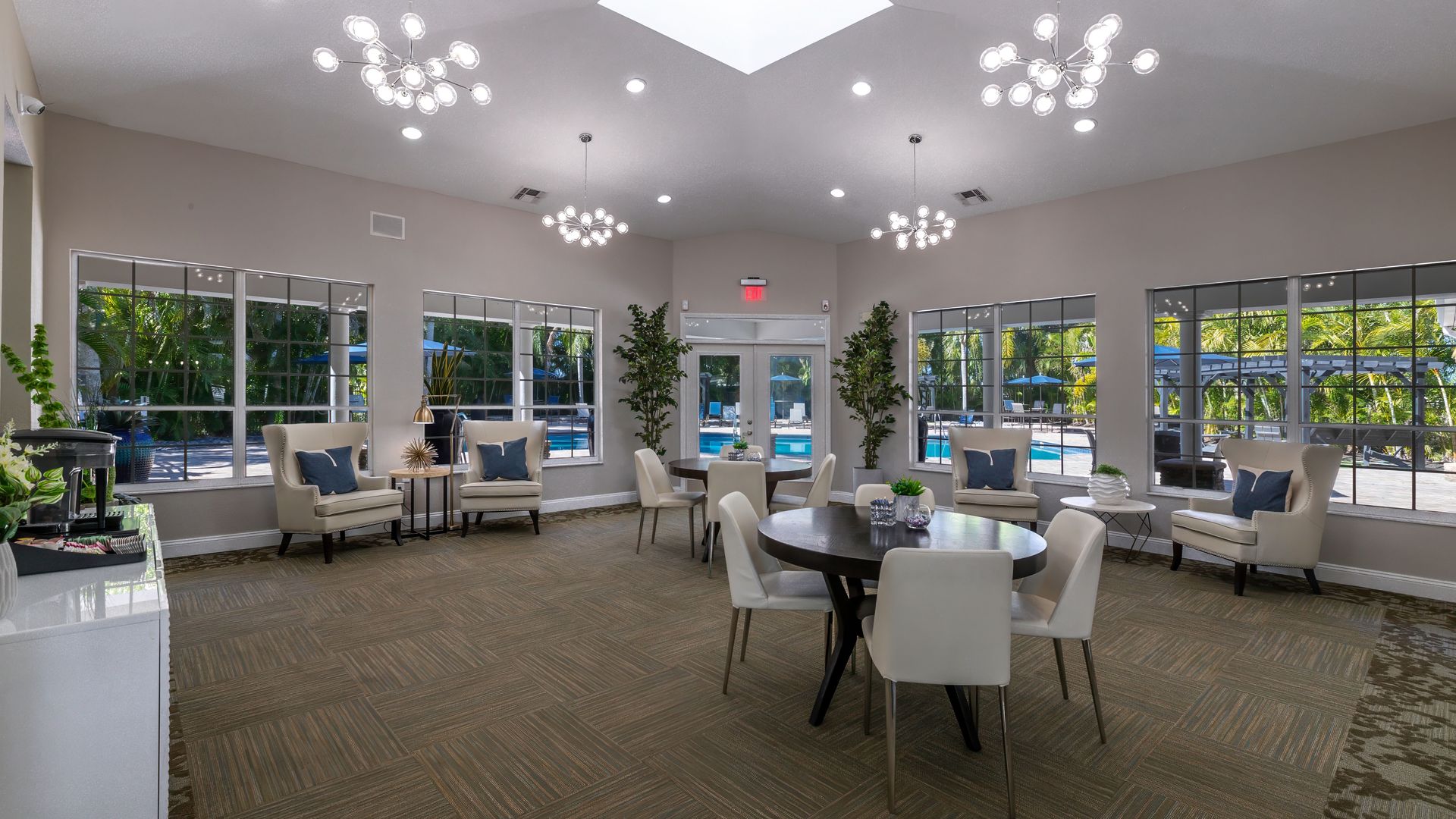 Community clubhouse at Meadow Lakes featuring stylish furniture, elegant lighting, and large windows overlooking the pool area.