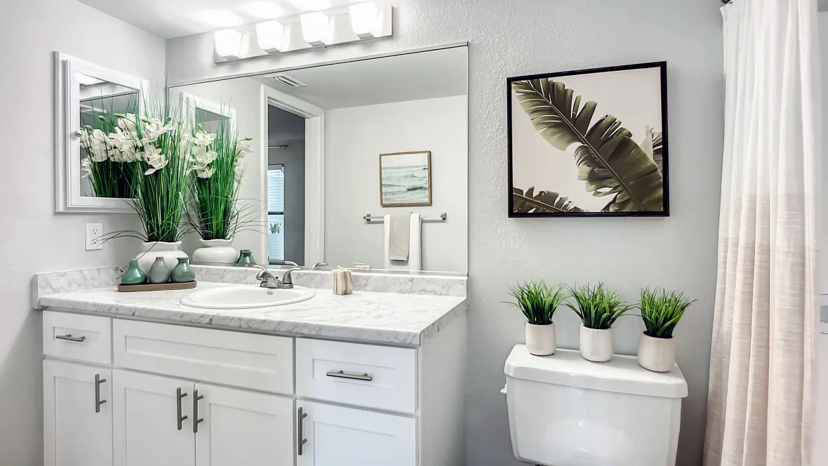 A sleek, modern bathroom adorned with spacious white cabinets and drawers beneath an extended white marbled vanity, creating an ambiance of sophistication.