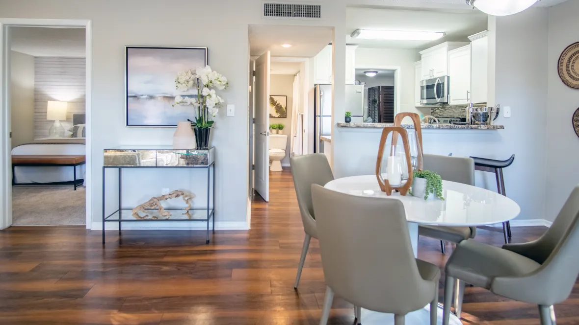 A dining room table and four chairs, with brush-nickel chandelier overhead for an elegant dining space, with easy views into the kitchen and master bedroom space for easy flow and effortless living.