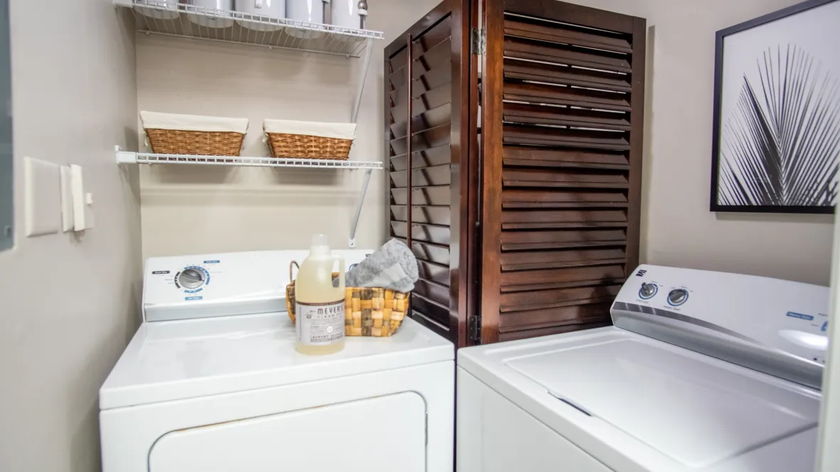 A pleasing laundry room adjacent to the kitchen, furnished with a full-size washer and dryer set, and overhead shelving for added convenience.