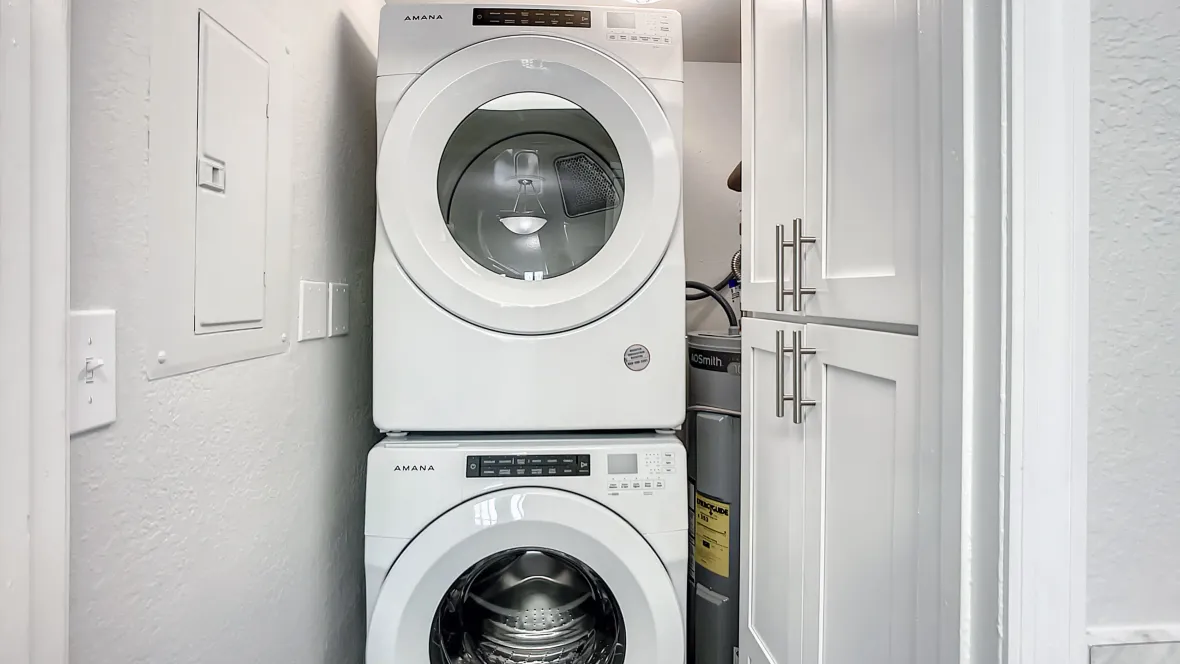 Stackable washer and dryer units in a well-lit laundry room, offering space-saving laundry solutions for residents.