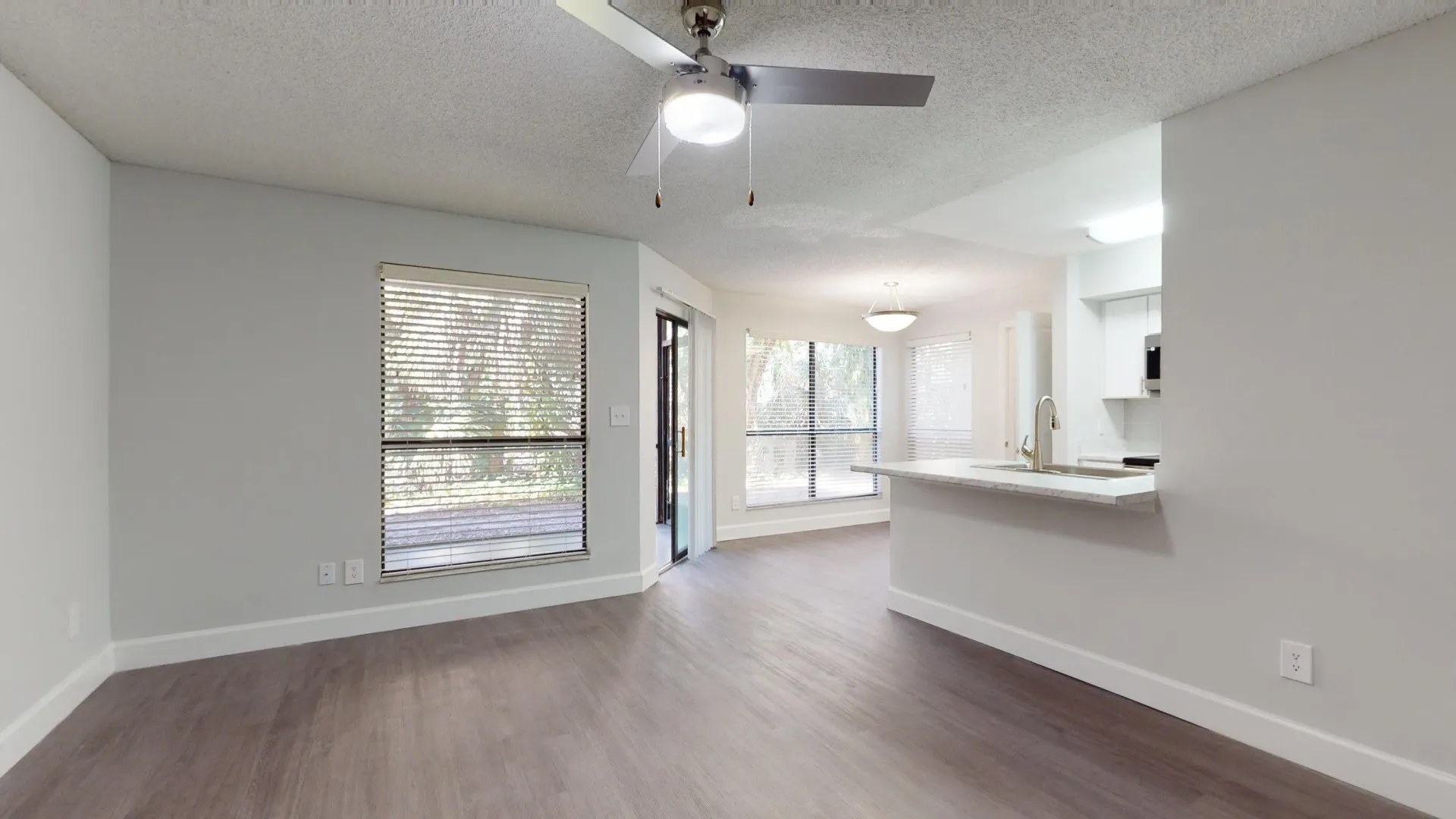 Open living and dining area in the Martinique floor plan, featuring large windows, a ceiling fan, and access to a private patio. 