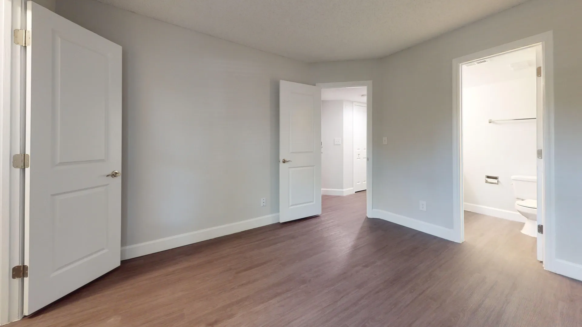 Master bedroom in the Martinique floor plan, showing a door leading to an ensuite bath and another door opening to the hallway, with modern flooring throughout.