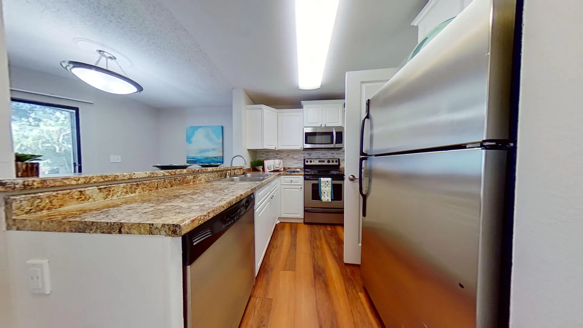 Kitchen with granite-style countertops, stainless steel appliances, and wood-style flooring in The Newport Autograph floor plan.