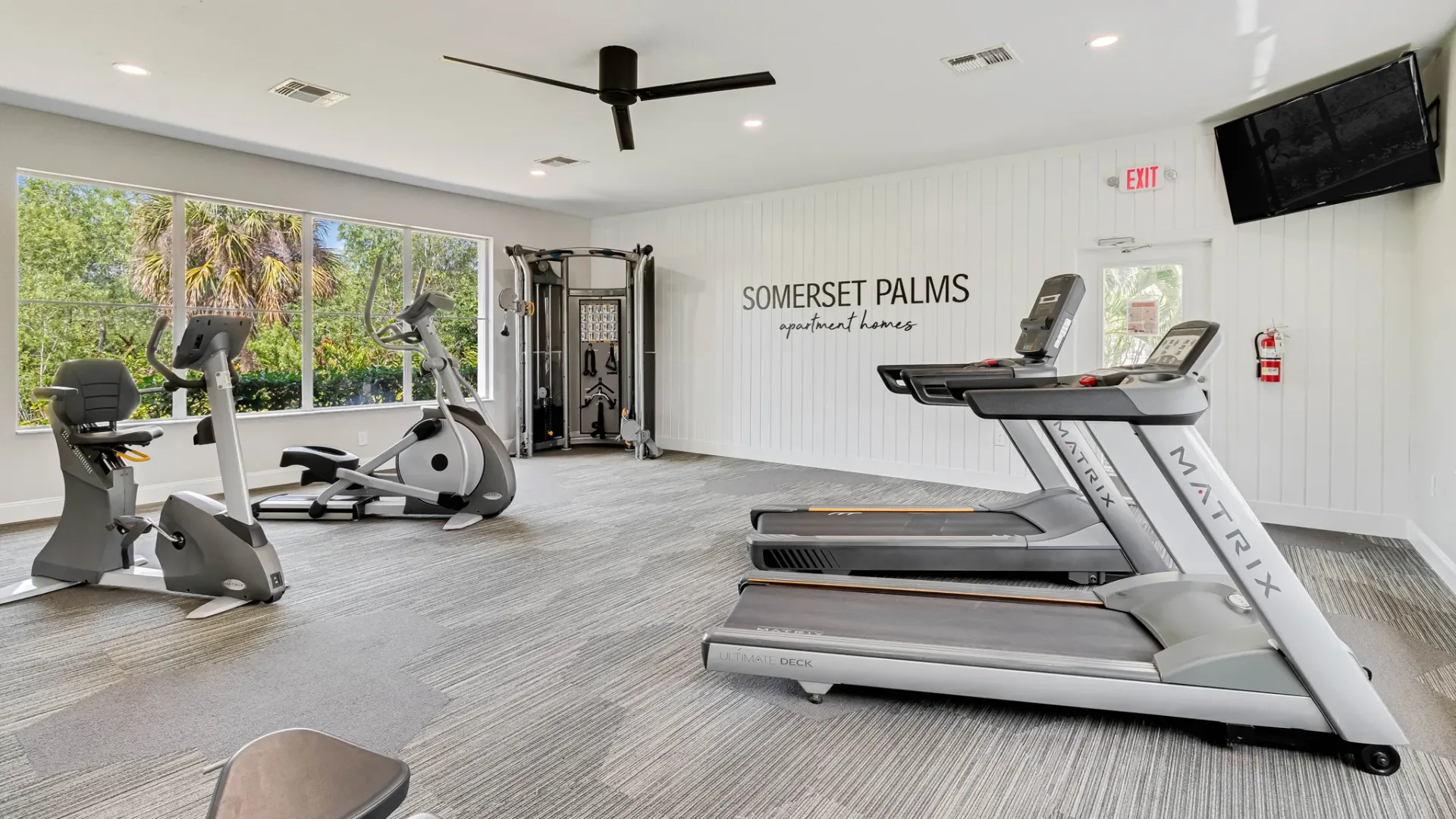 Bright fitness room at Somerset Palms with treadmills, bikes, and strength machines.