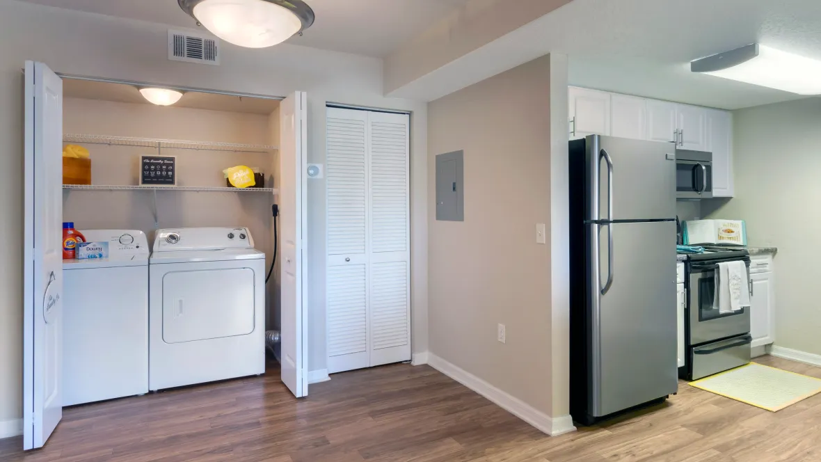 A laundry room equipped with a full-size washer and dryer set with ample storage above