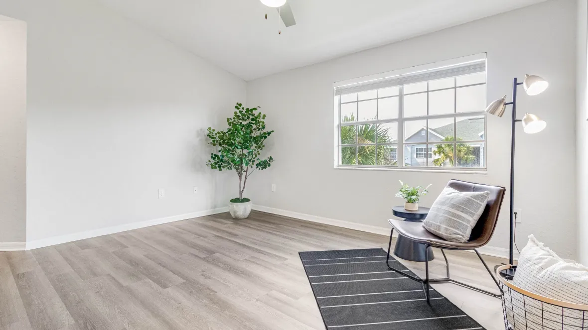 A cozy living room basking in natural light from expansive windows, boasting an elegant ceiling fan