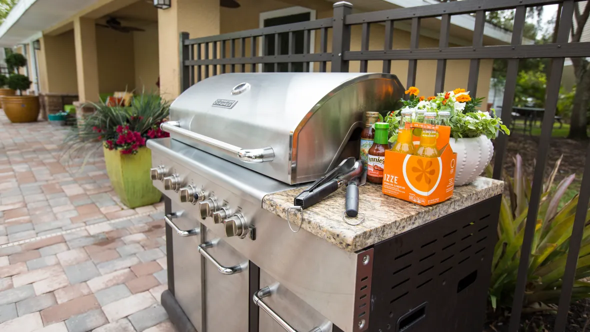A gleaming stainless-steel gas grill nestled within the gated pool area