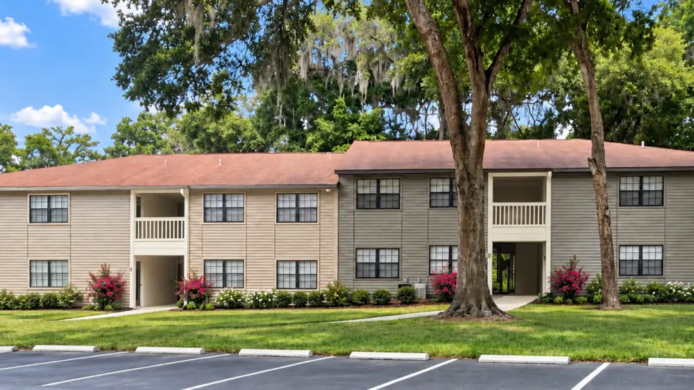 Carrington Lane apartment building with mature trees and landscaped grounds, showcasing a new exterior paint color scheme coming soon.