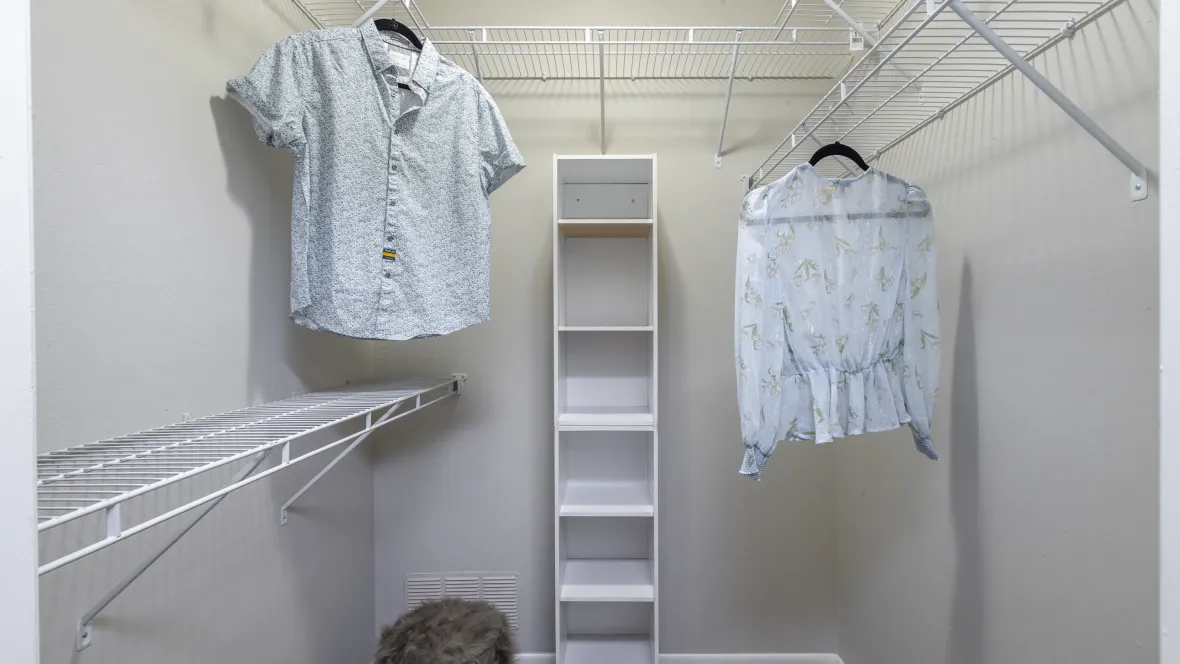 A walk-in closet with numerous shelves, designed to maximize storage for all your wardrobe essentials, and more.