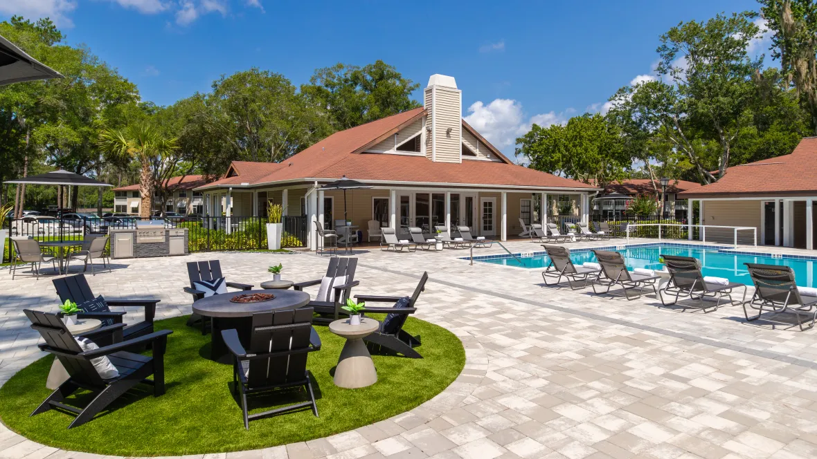 An inviting fireside oasis featuring a firepit, surrounded by Adirondack seating on the large paved pool deck, designed for daytime or evening fireside chats.