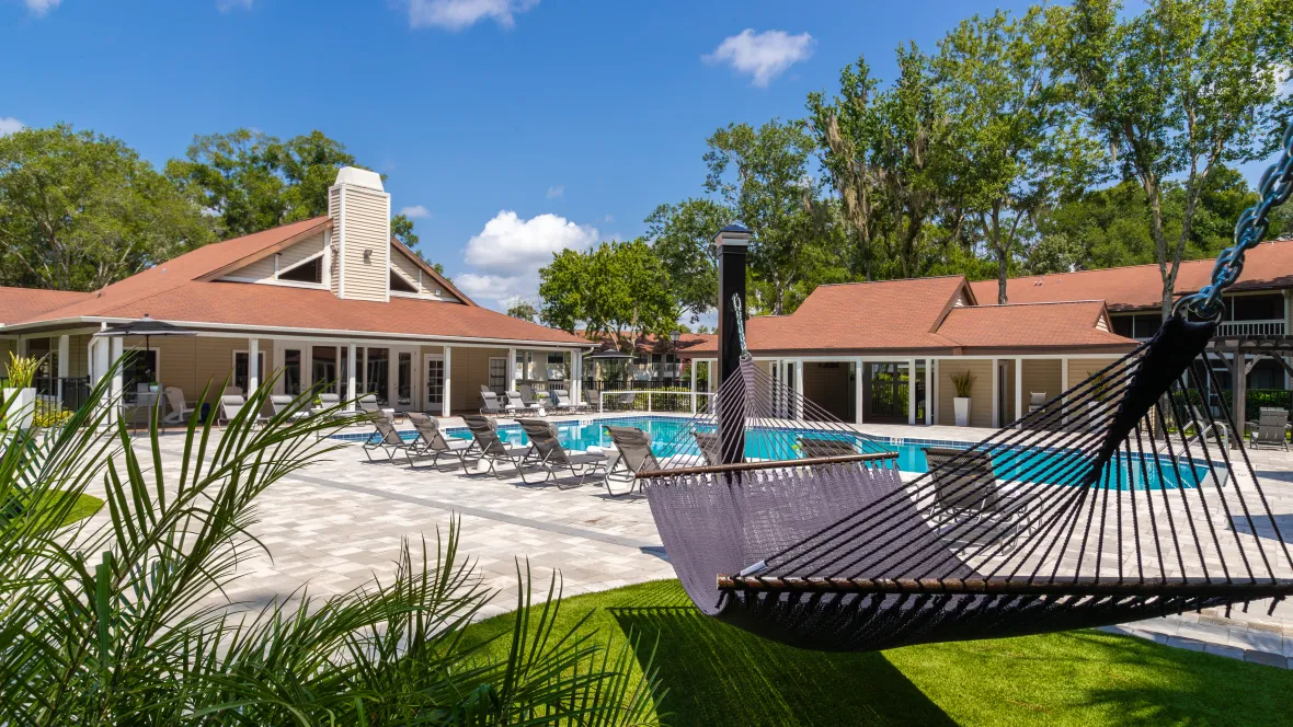 Experience the expansive pool deck, with inviting hammocks, set against a tranquil blue pool and cozy cabana.