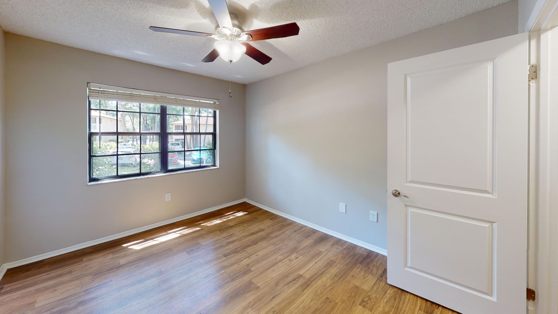 Bedroom in The Oakwood floor plan at Carrington Lane featuring wood-style flooring, a ceiling fan, a large window, and large windows.