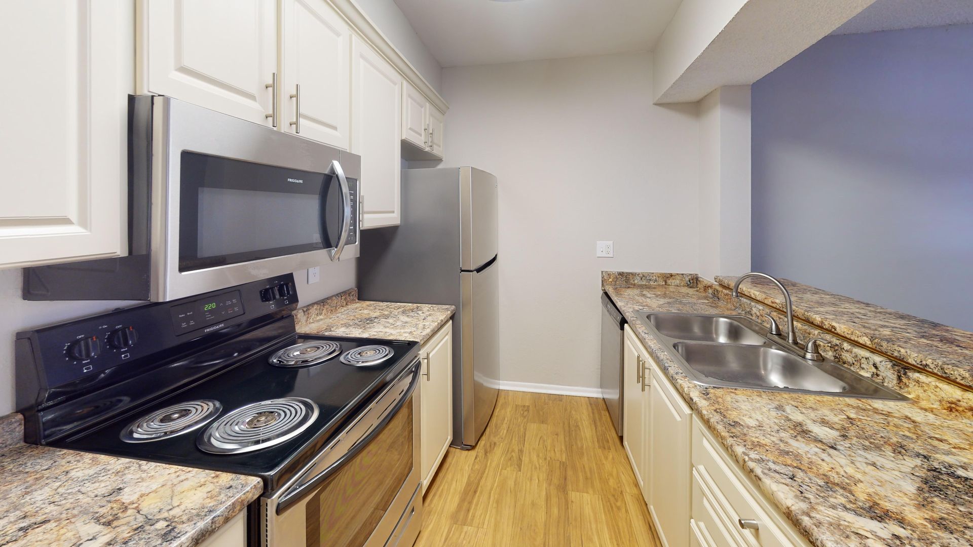 Kitchen in The Oakwood floor plan at Carrington Lane featuring stainless steel appliances, granite-style countertops, white cabinetry, and expansive countertops. 