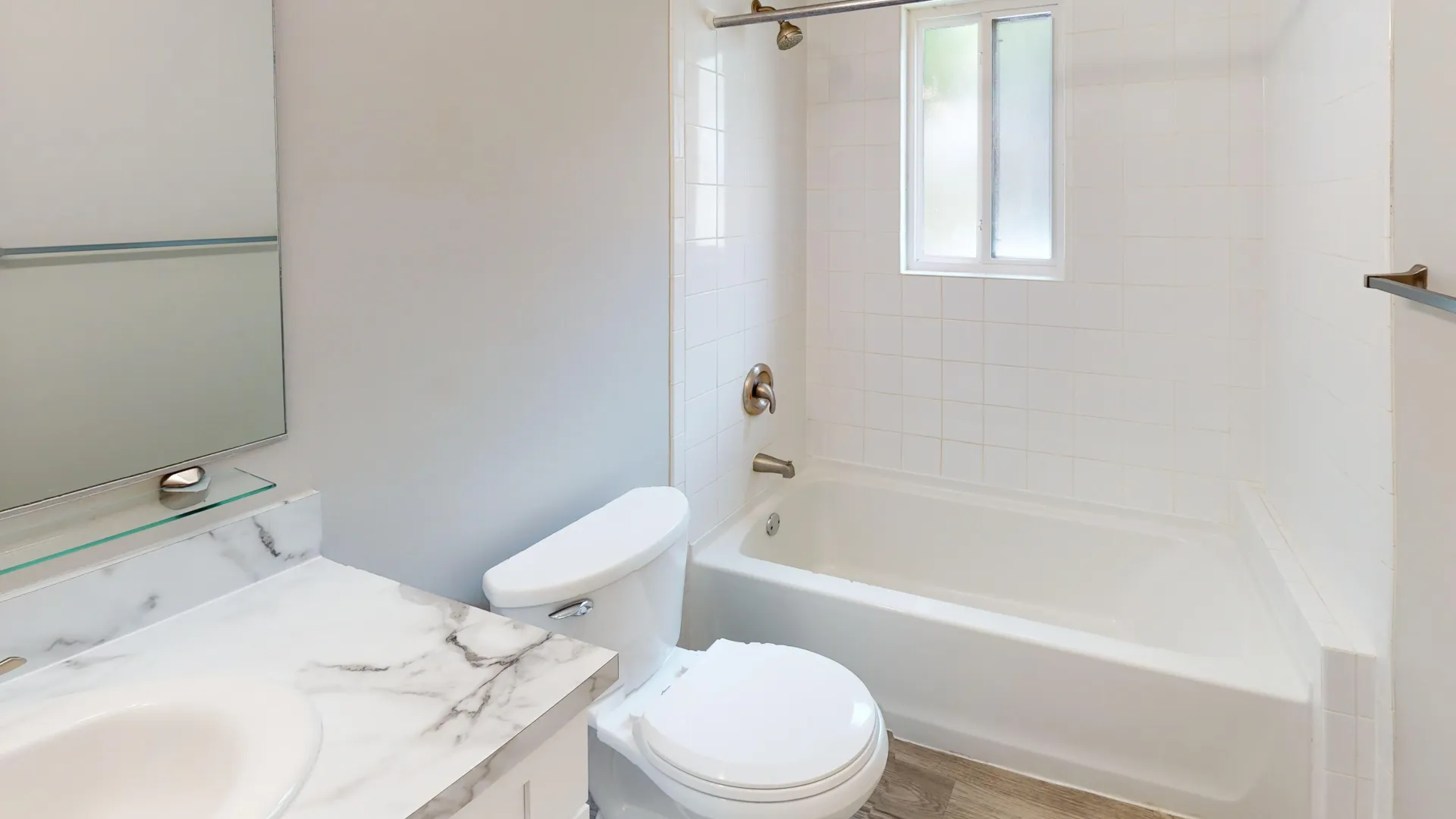 The Rosewood bathroom at Carrington Lane with a marble-look vanity, large mirror, full tub-shower combination.