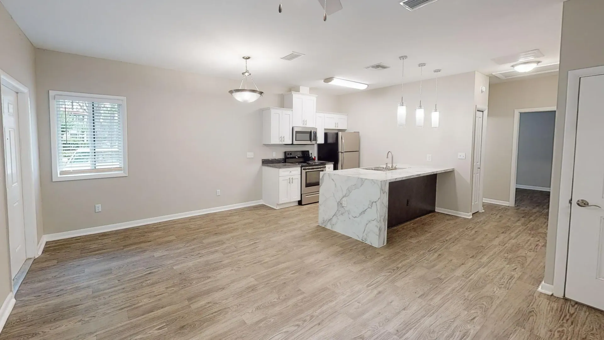 Open kitchen and dining area in The Rosewood floor plan featuring a breakfast bar, stainless steel appliances, white cabinetry, and wood-style flooring.