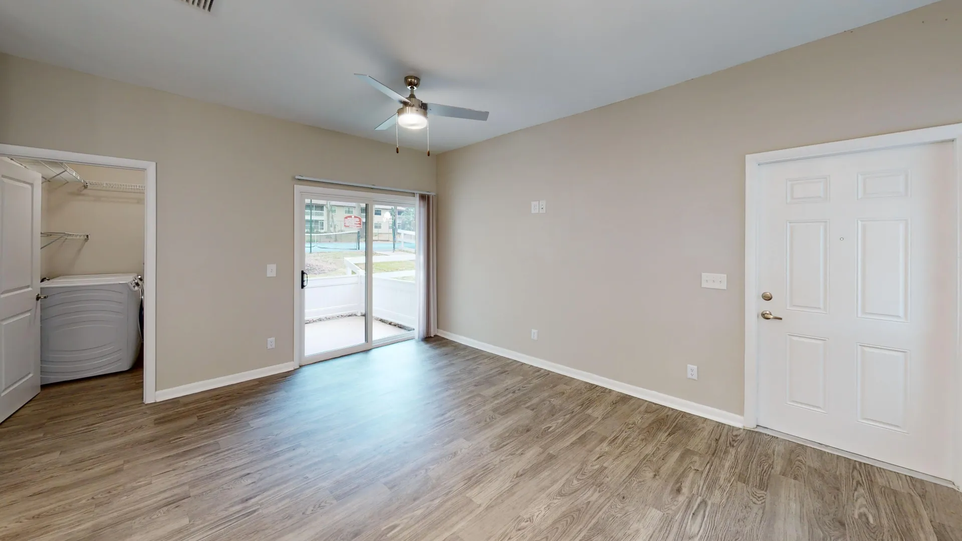 Open living room in The Rosewood floor plan featuring wood-style flooring, a ceiling fan, and sliding glass doors leading to a private patio.