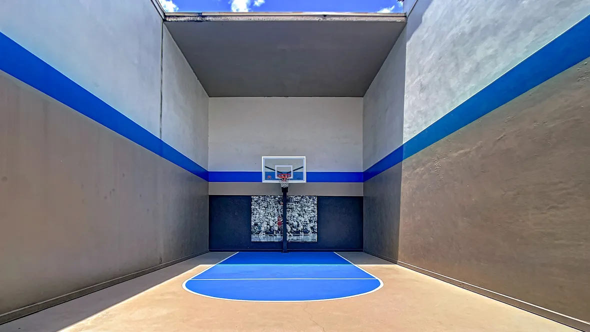 A basketball court enclosed by four walls with open-air roof.
