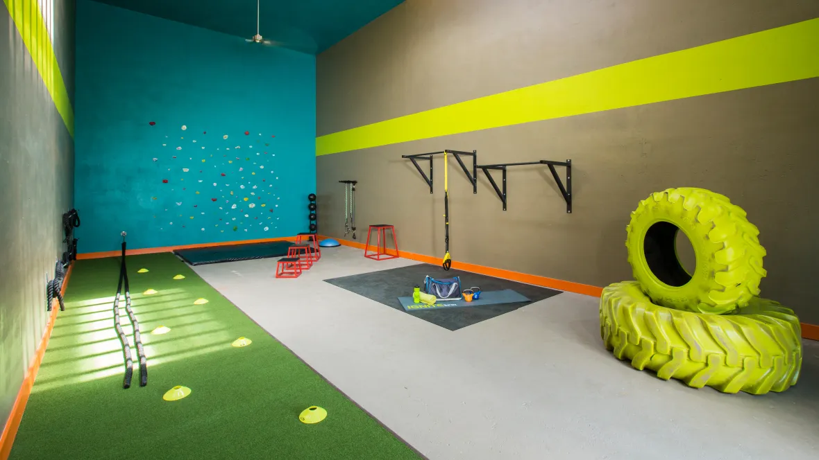 A dynamic CrossFit gym with a variety of workout equipment, tires, and rock wall.
