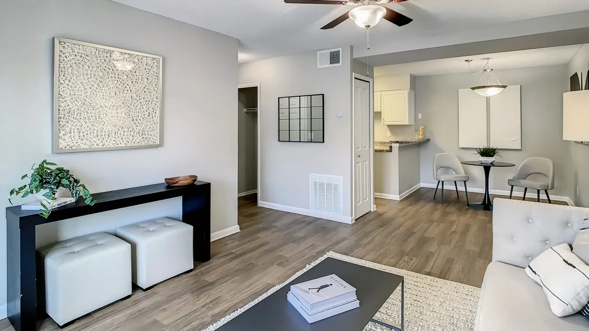 A spacious living room featuring a ceiling fan and connected dining area, flooded with natural light.