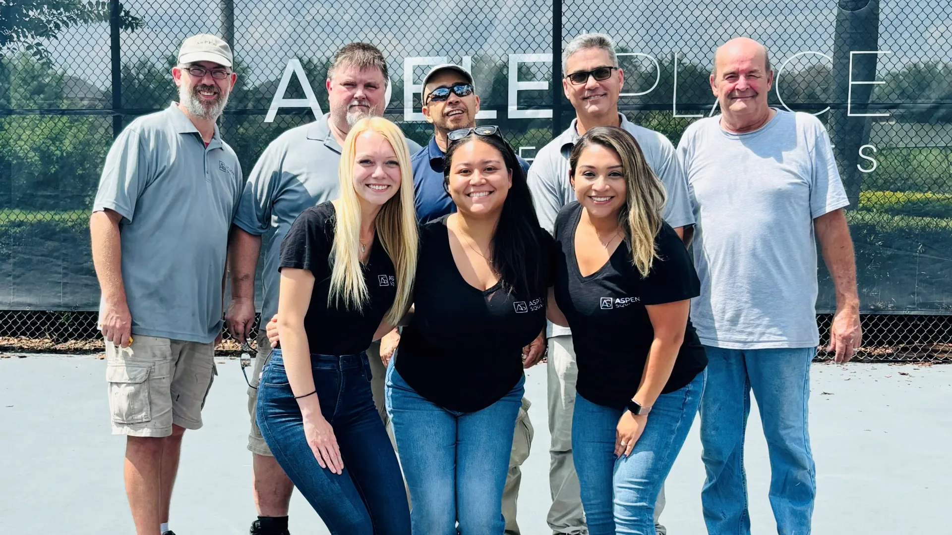 the maintenance and leasing staff on the tennis court of the community