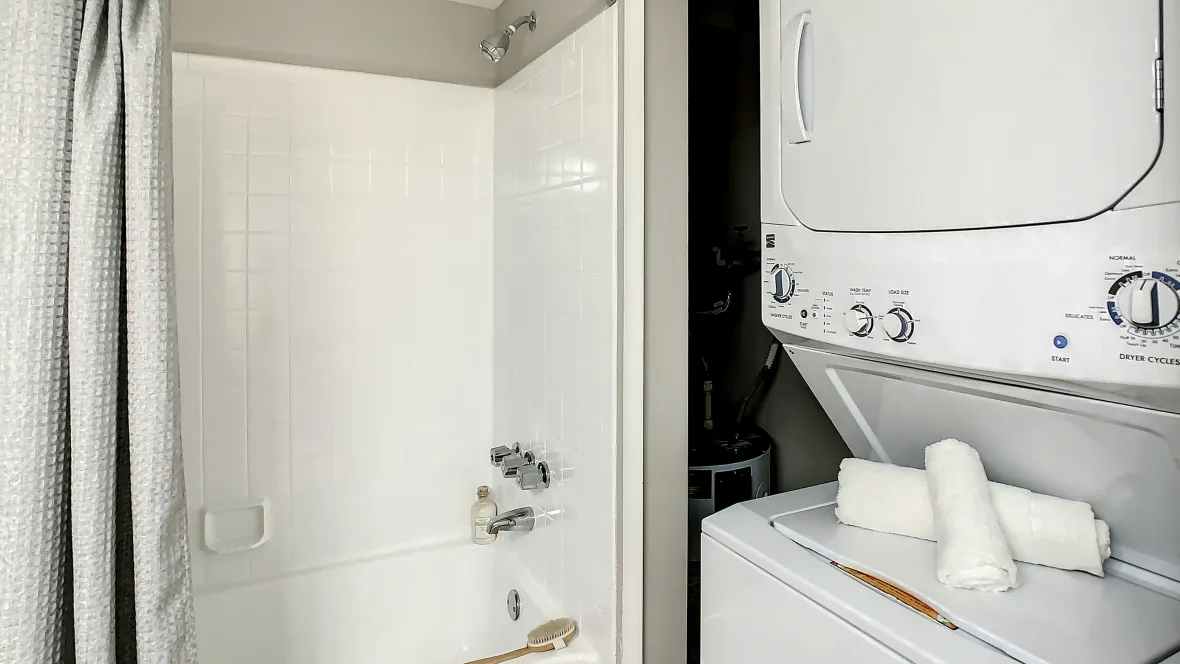 A stackable washer and dryer in a closet within the bathroom.