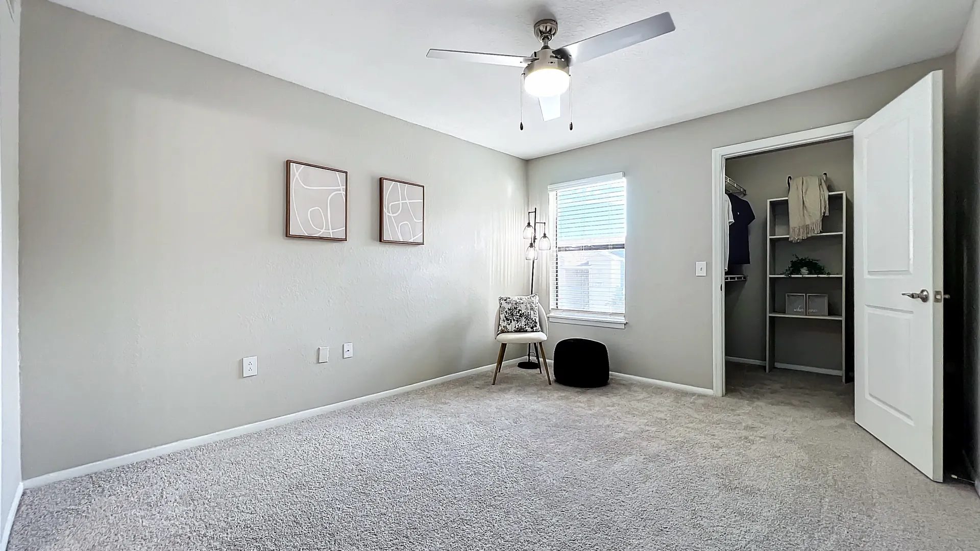 Cozy bedroom with plush carpeting, modern decor, a ceiling fan, a large window, and a spacious closet.