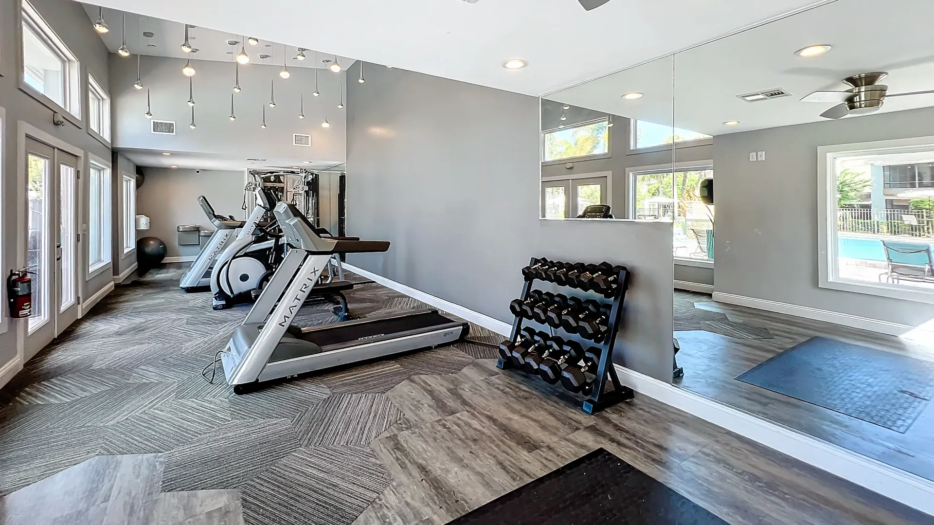 Fitness center with treadmills, free weights, and a view of the pool.