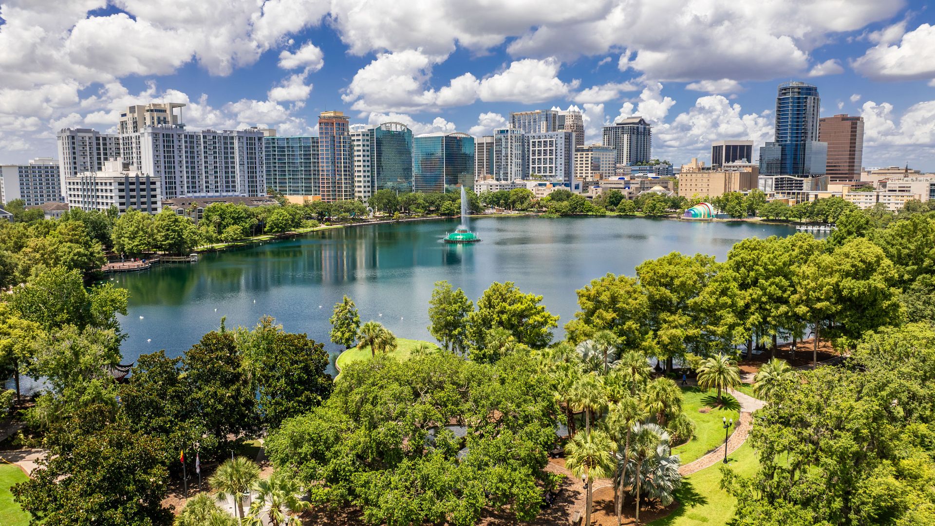 Aerial view of Lake Eola with central fountain and downtown Orlando skyline in the background.