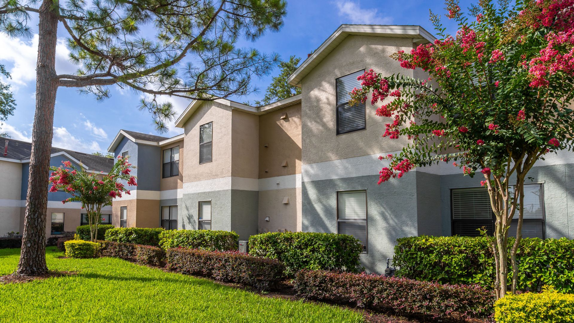 Exterior view of Harper Grand Apartments in Orlando with manicured landscaping and mature trees.