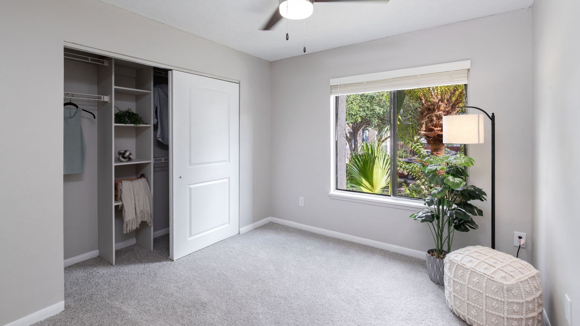 Modern apartment bedroom with closet storage and large window.