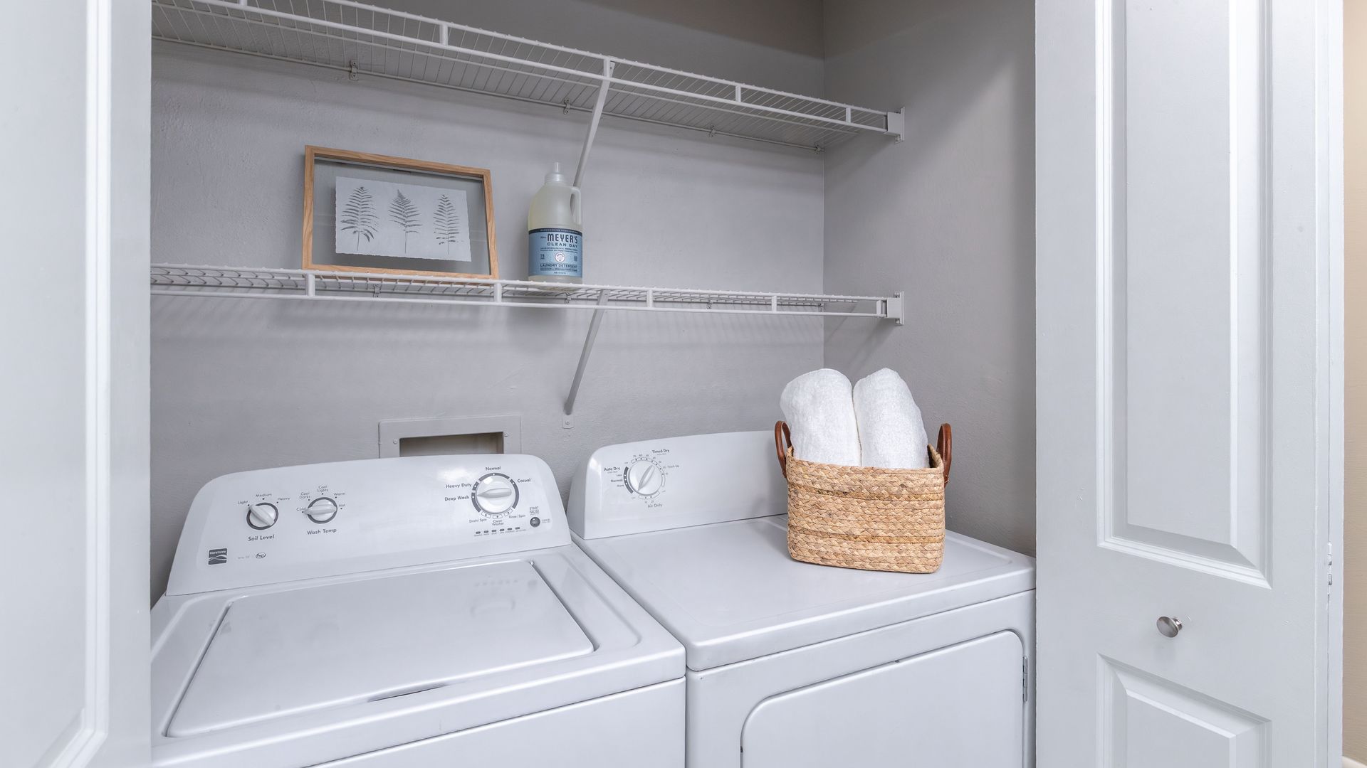 Full-size in-unit washer and dryer with overhead shelving.