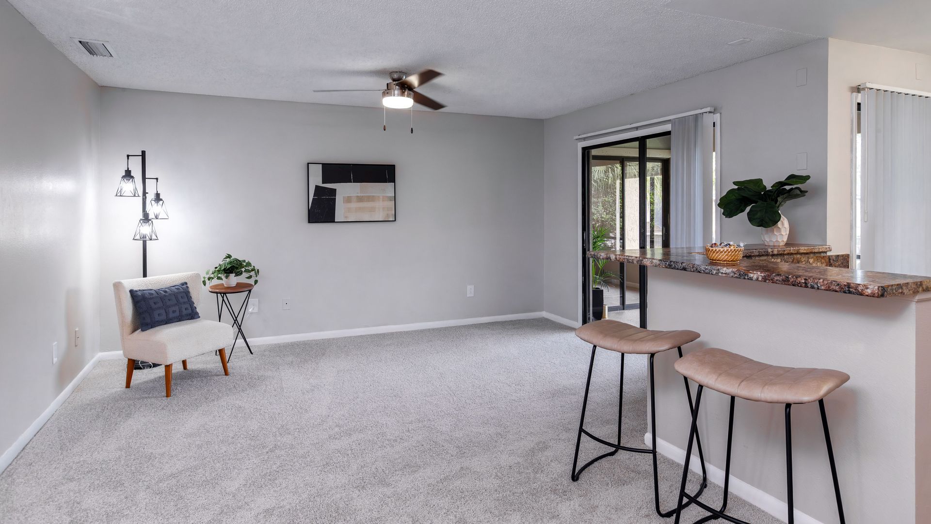 Living room with modern decor, breakfast bar, and patio access at Harper Grand Apartments.