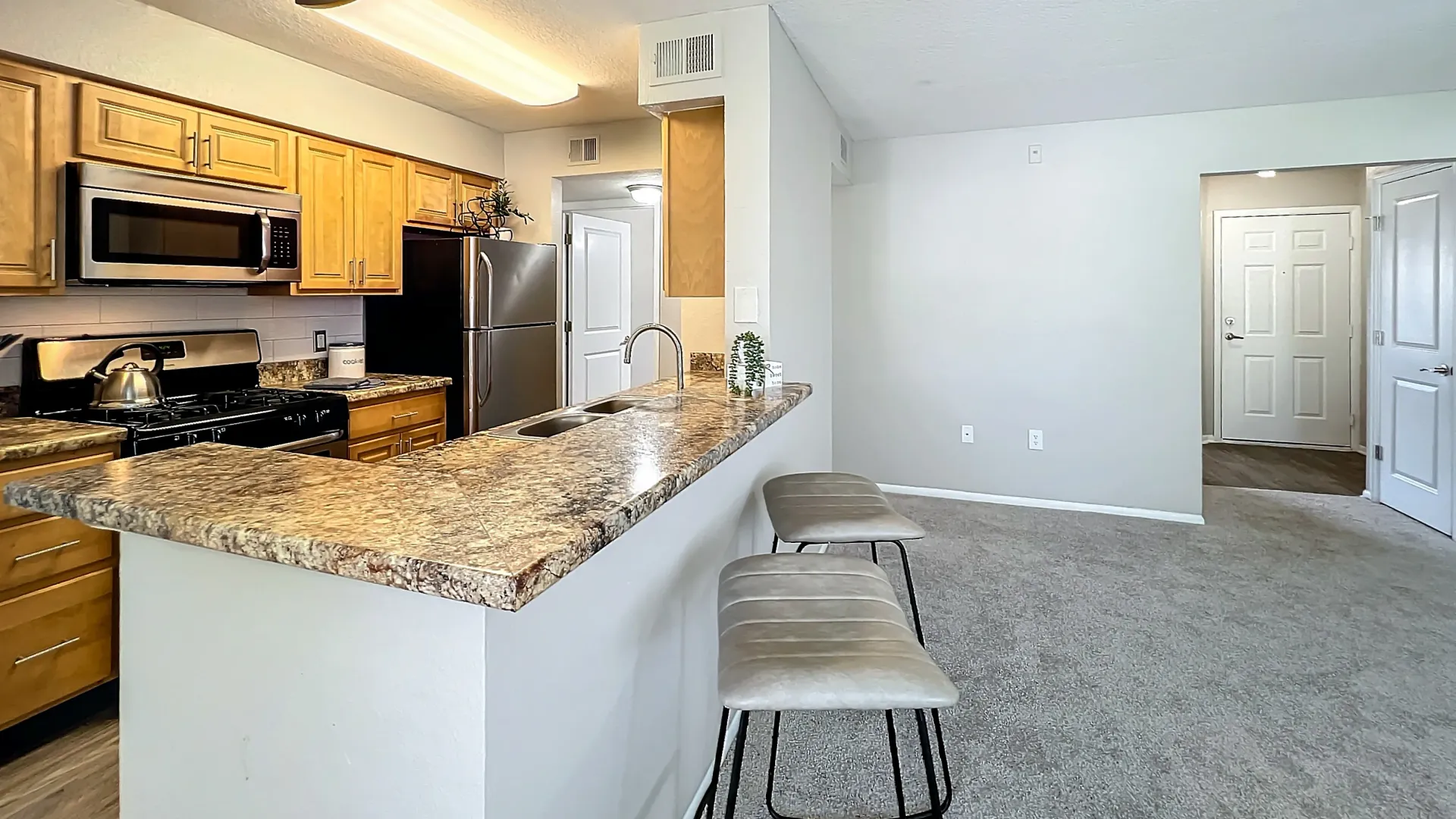 Modern kitchen with a breakfast bar, granite-style countertops and stainless steel appliances.