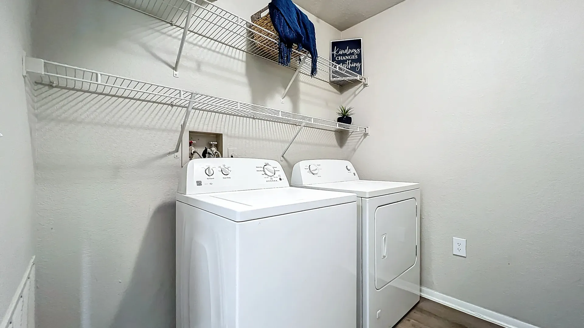 In-unit laundry room with a full-size washer and dryer and spacious shelving.