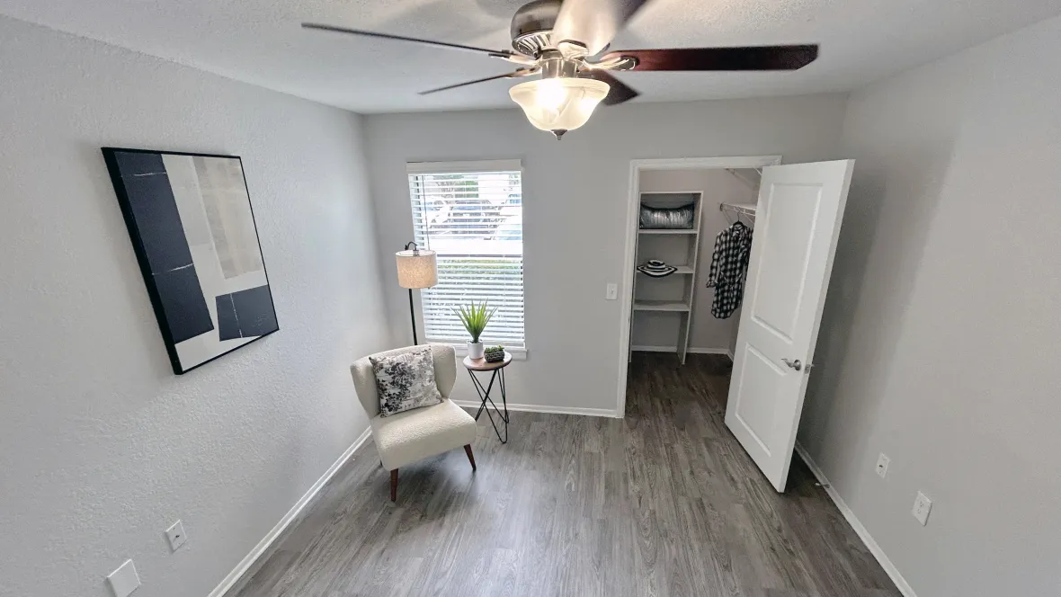 An elegant master bedroom featuring wood-like flooring, ample windows, and a roomy walk-in closet, offering an enchanting retreat within your home.