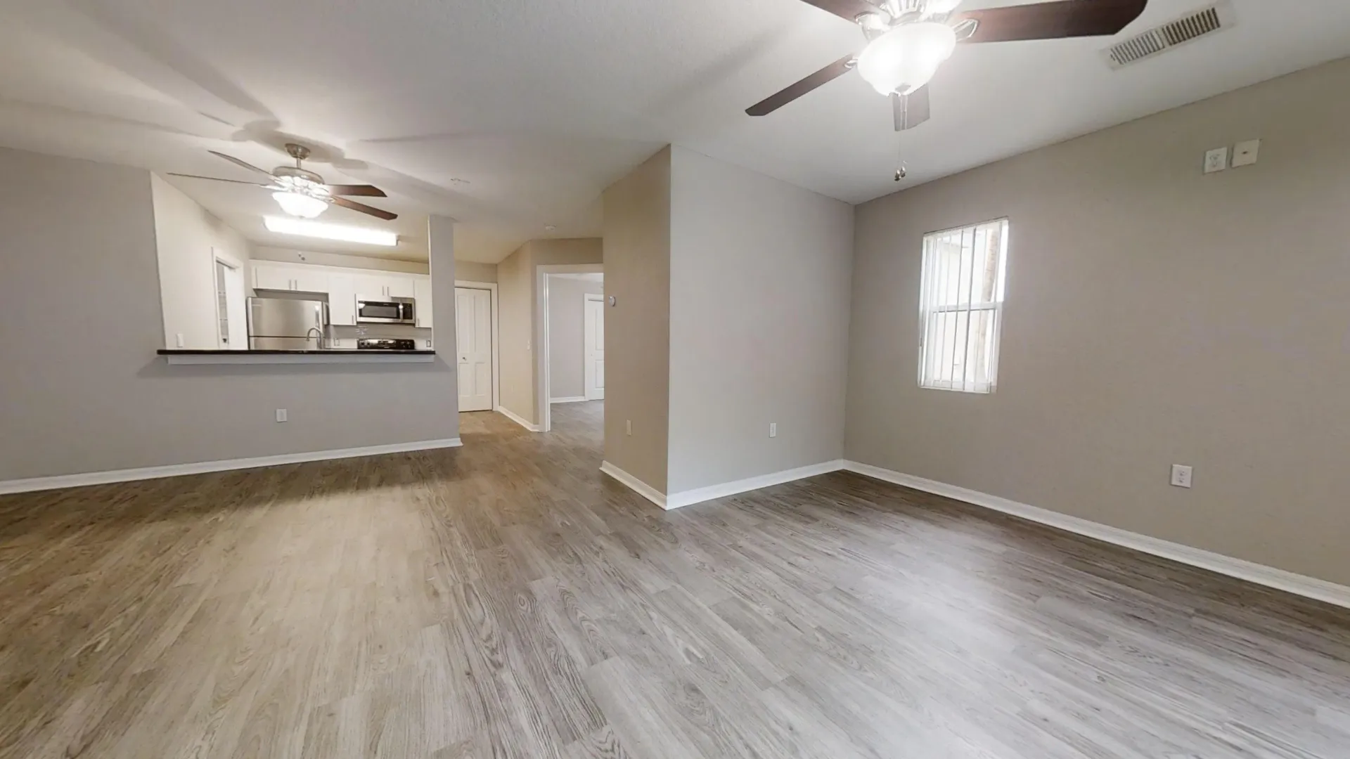 Open living space in The Chateau floor plan at Harper Grand Apartments with wood-style flooring and updated kitchen.