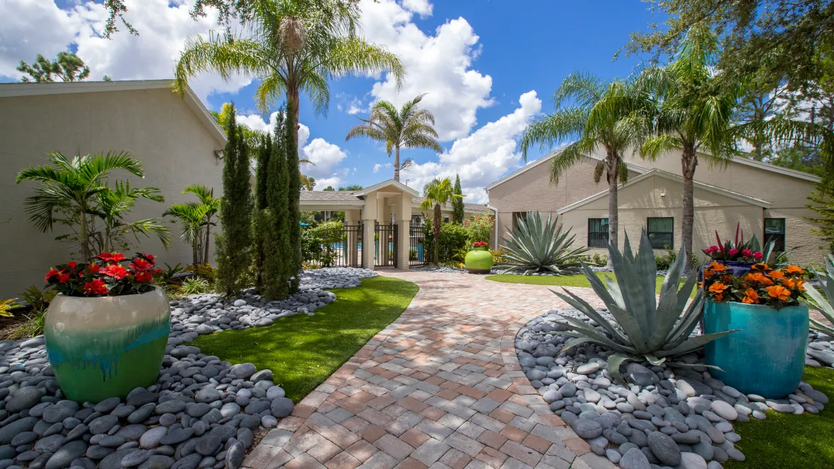 A paved walkway leading to the gated pool, surrounded by vibrant tropical landscaping, offering a magical place to call home.