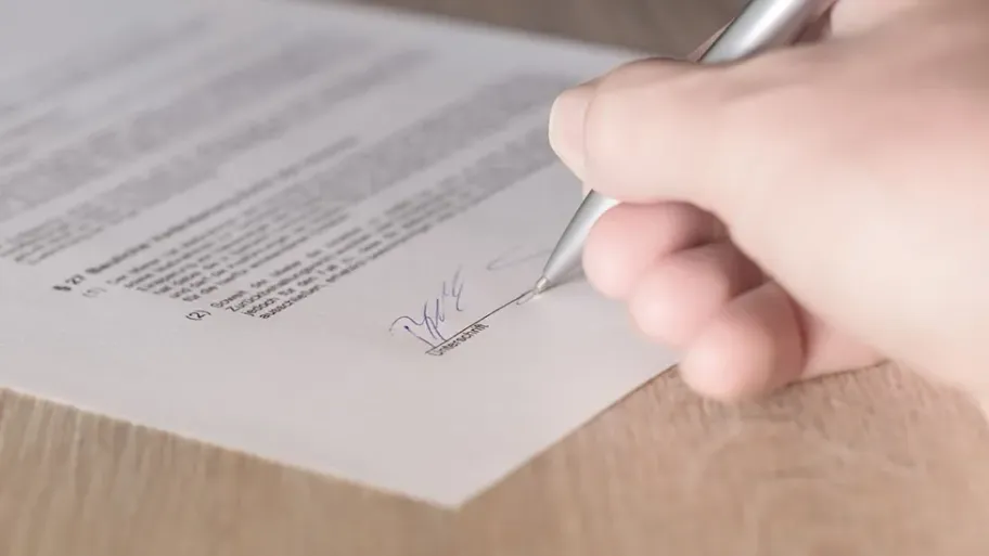 A close-up of a hand signing a lease document