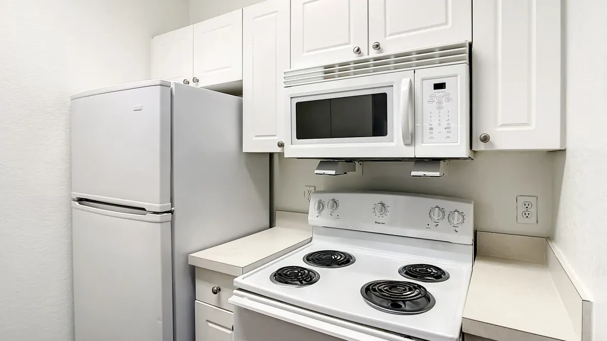 A fully equipped classic kitchen with timeless white cabinetry and all appliances, including a refrigerator, oven, and conveniently placed microwave over the stove. 
