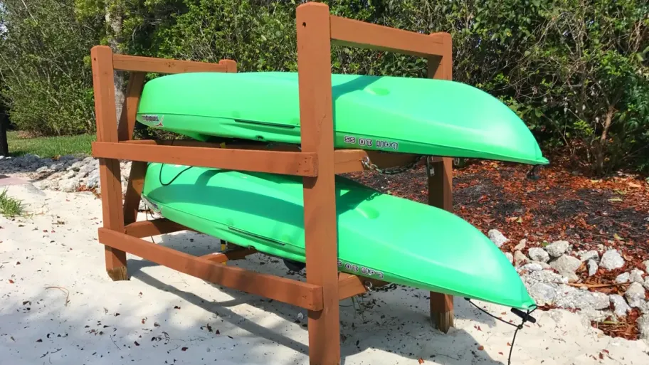 Green kayaks stacked on a sandy beach, available for rent to residents – a convenient water adventure at your doorstep awaits.