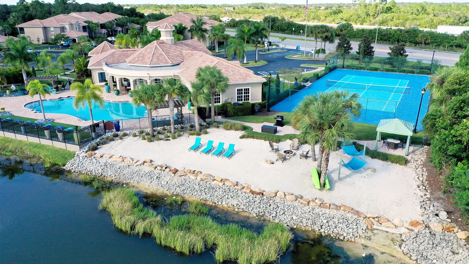An aerial view of the clubhouse, beach, tennis court, and lake